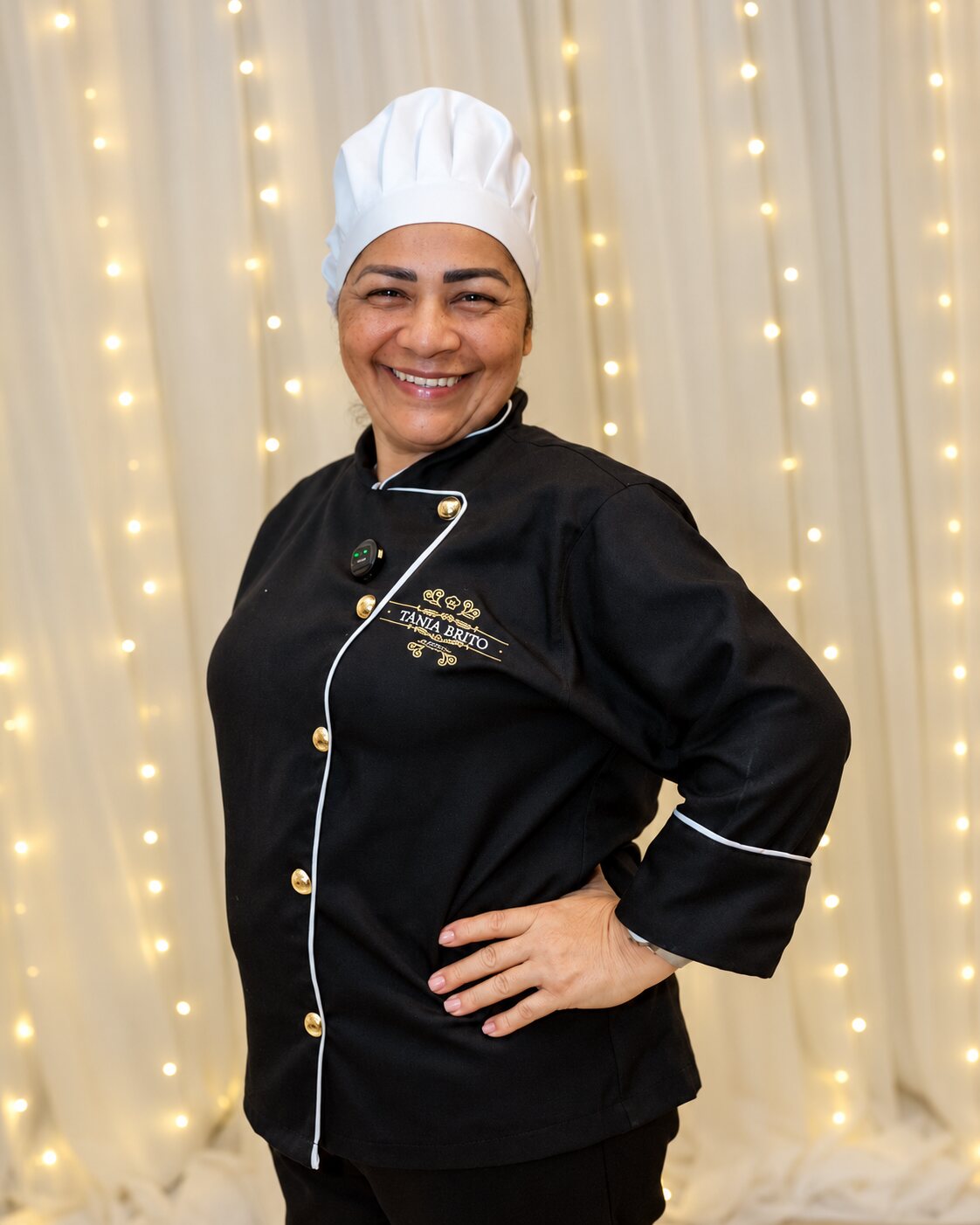 Tânia Brito sorrindo com seu uniforme de chef